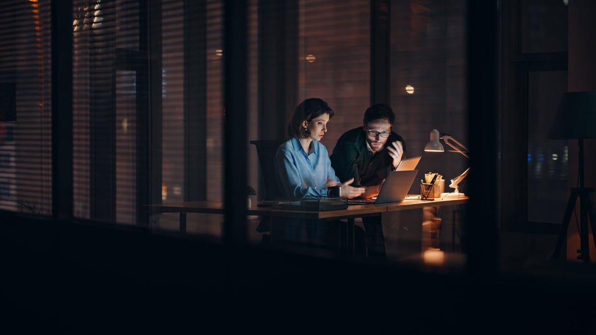 Overloaded business owner stressed at laptop late at night, questioning marketing performance