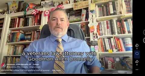 A man in a blue shirt and tie sitting in front of bookshelves, identified as a veterans law attorney with Goodman Allen Donnelly