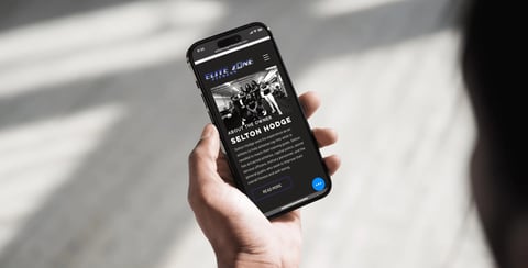 Hand holding smartphone displaying a dark-themed app interface with text content and a blue button