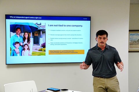 Man in dark shirt presenting slide about independent agent status to audience