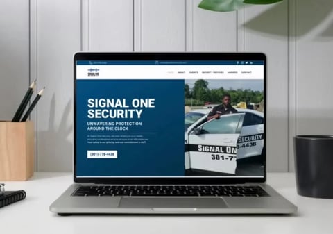 Laptop displaying Signal One Security website with security guard and patrol vehicle