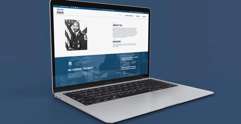 Silver laptop displaying a modern website with navigation menu and about us section